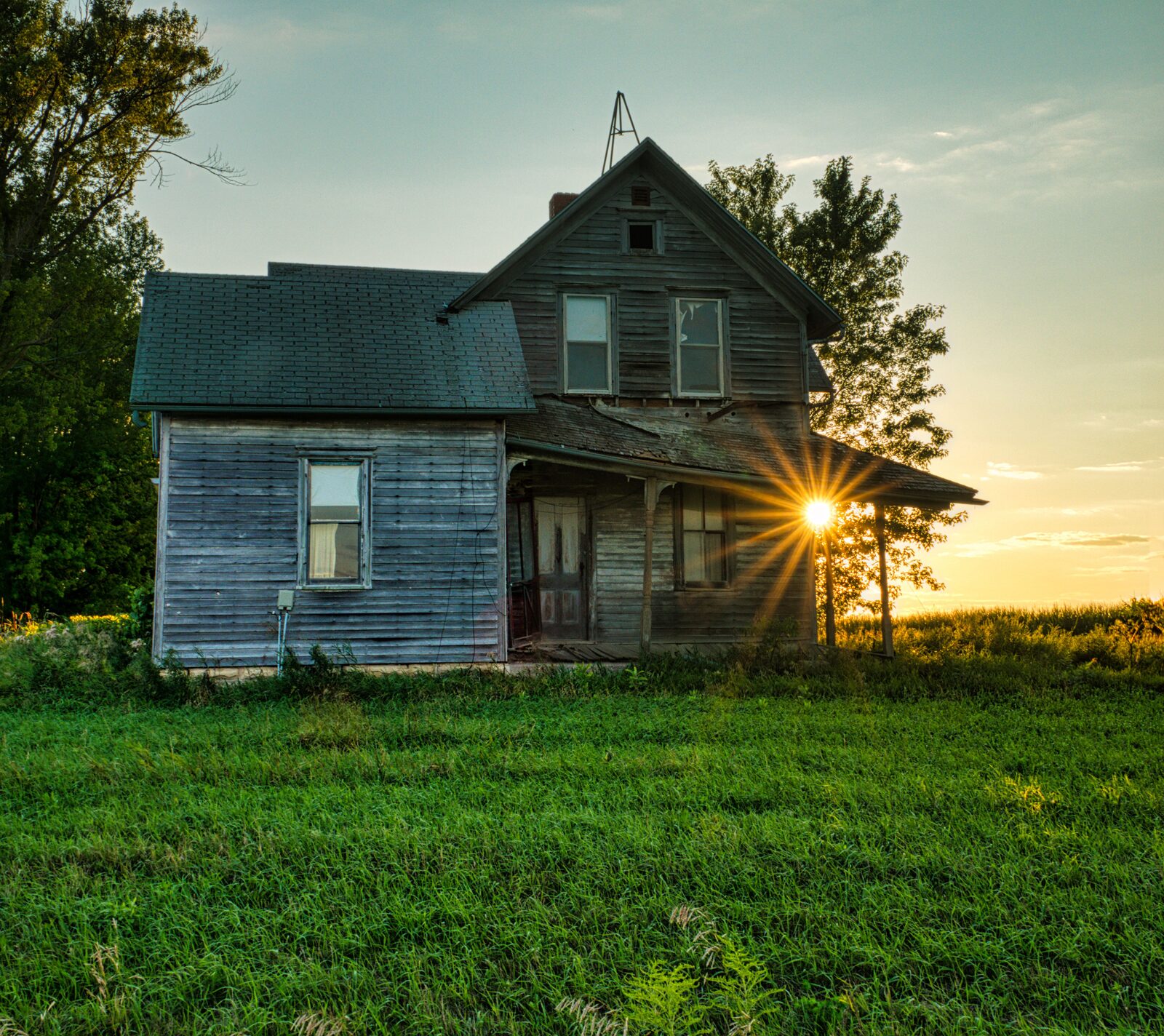 A weathered farmhouse and silo standing against a grey winter sky